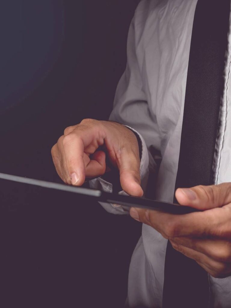 Businessman holding a tablet with futuristic digital icons and globe.